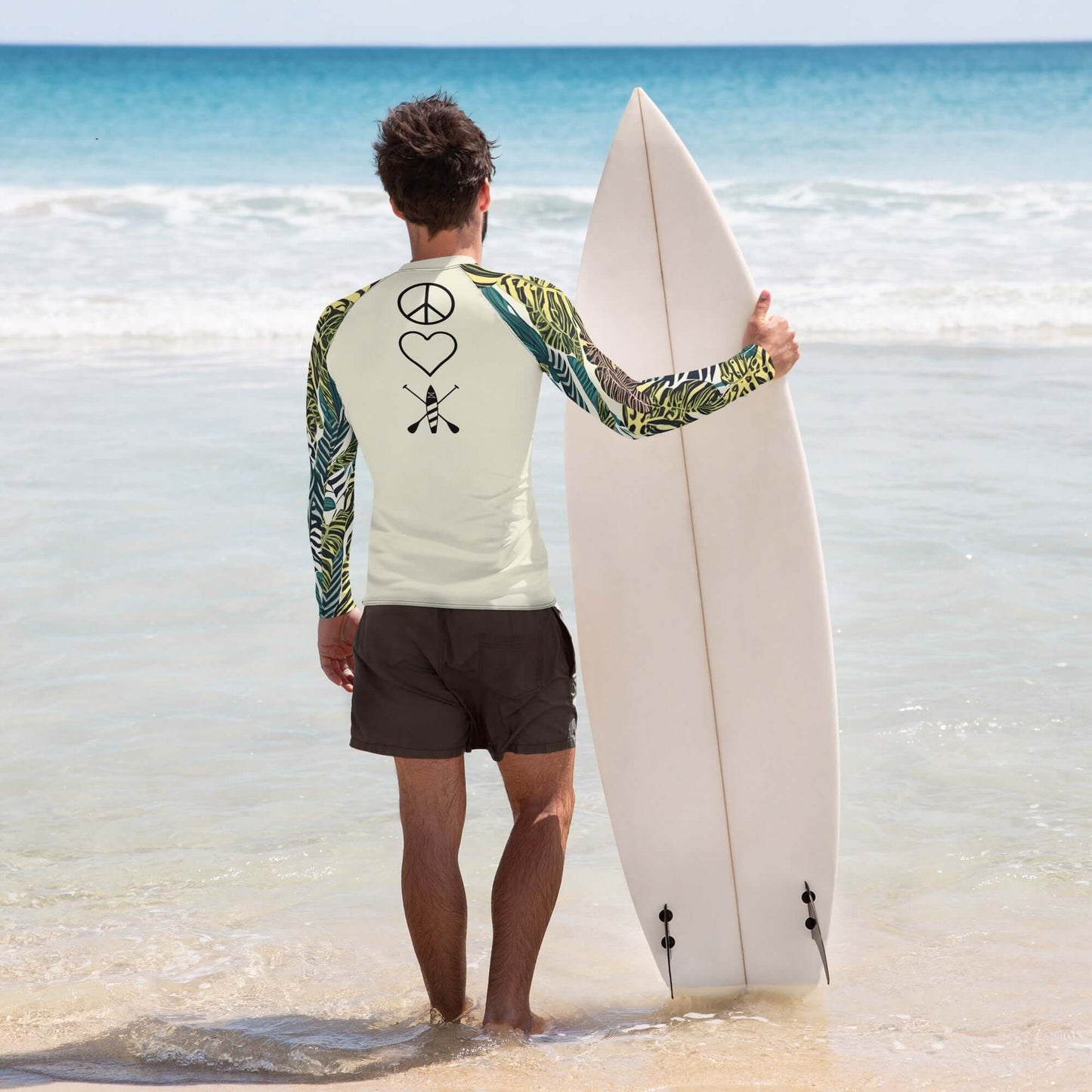 Man in psychedelic rash guard holding surfboard on the beach, ready for adventure in the sun.